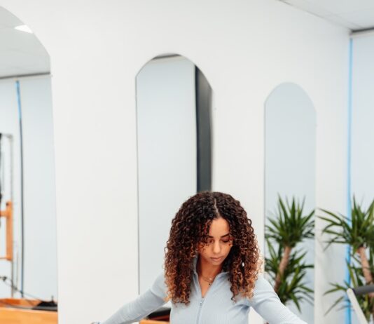 필라테스와 요가를 활용한 전신 건강법 a woman sitting on a piyor in a gym