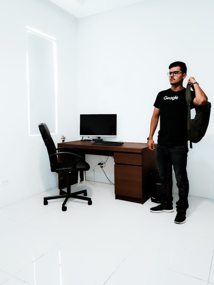 Photo by Fernando Hernandez man standing near brown desk beside white wall