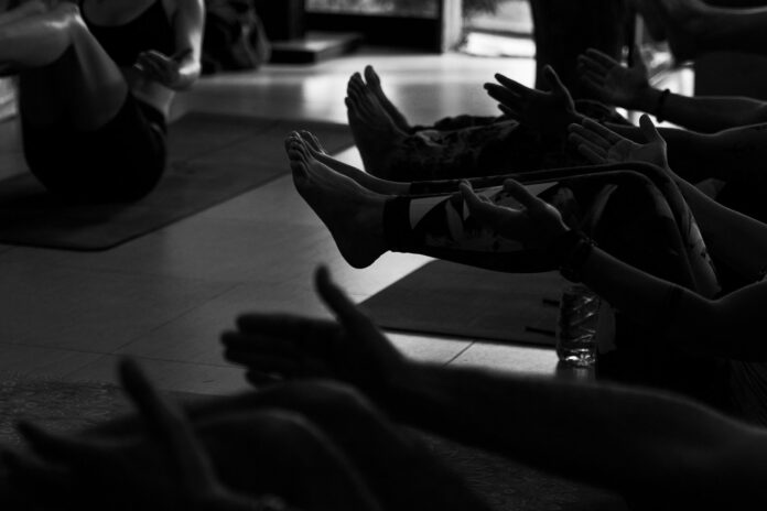 Photo by Christian Harb People exercising on yoga mats in a studio.