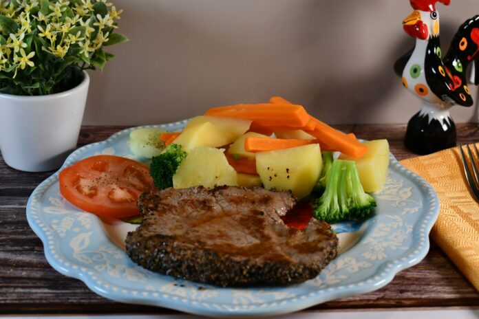 Steak with boiled potatoes, carrots, broccoli, and tomato