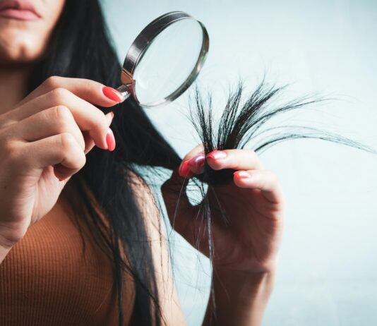 집에서 시작하는 건강한 모발 관리, 최신 트렌드와 실천 팁 Woman examining split ends of hair with magnifying glass