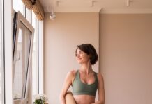 “필라테스로 달라진 일상… 집에서도 가능한 실천 루틴 인기” a woman in a green sports bra top and leggings holding a yoga mat